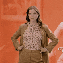 a woman with her hands on her hips is wearing a brown jacket and a leopard print shirt