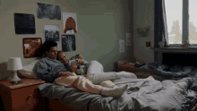 a man and woman laying on a bed with posters on the wall including one that says ' a ' on it