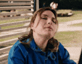 a woman in a blue denim jacket is making a face