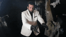a man in a white suit and black gloves is standing in a dark room