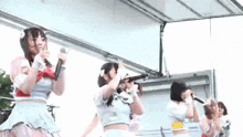 a group of young women are singing into microphones on stage .