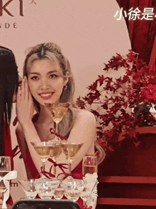 a woman in a red dress sits at a table with wine glasses and a sign that says ki