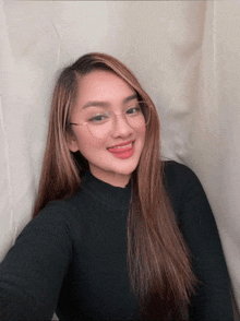 a woman wearing glasses and a black sweater is smiling