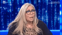 a woman wearing glasses and a leopard print top is on a television screen
