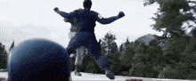 a man in a blue uniform is jumping in the air while another man watches .