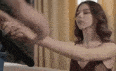 a woman in a red dress is holding a man 's arm while standing on a bed .