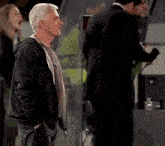 a man in a black jacket is standing in a dark room