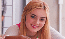 a woman with blonde hair and blue eyes is smiling for the camera