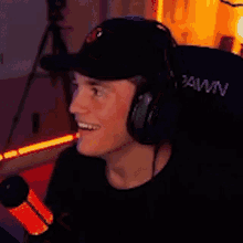 a man wearing headphones and a baseball cap is sitting in front of a microphone .