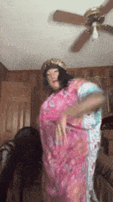 a woman in a pink dress is dancing in a room with a fan and a ceiling fan