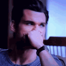 a man wearing a watch is covering his nose with his hand