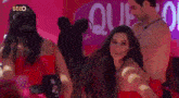 a woman in a red dress is dancing with a man in a pink room .