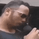 a man wearing sunglasses is smoking a cigarette .