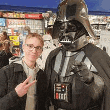 a man dressed as darth vader is standing next to a man dressed as storm trooper .