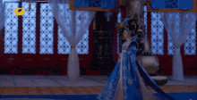 a woman in a blue and white dress is walking in a room
