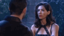 a man and a woman are standing next to each other and the woman is wearing a harness and necklace .