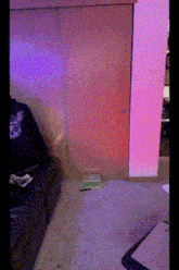 a person sitting on a couch in a room with a purple wall