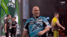 a man in a blue and white shirt is walking on a stage .