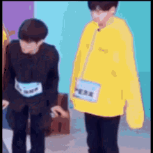 a blurry picture of two young men standing next to each other . one of the men is wearing a yellow sweatshirt .