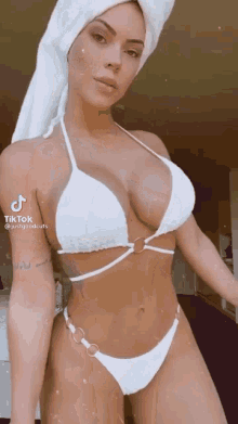 a woman in a bikini with a towel around her head .