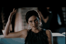 a woman in a black top is making a peace sign with her hand