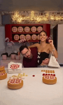 a man and a woman are posing for a picture in front of a display of cookies