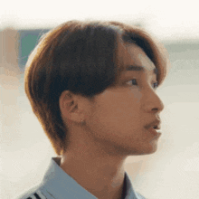 a close up of a young man 's face with a blue shirt and earrings .