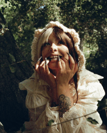 a woman with long nails and a tattoo on her arm is wearing a knitted hat