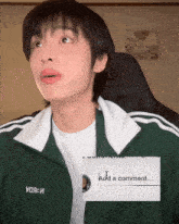 a man wearing a green adidas jacket has a white t-shirt underneath it that says yoa-i