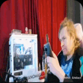 a man is holding a phone in front of a computer case that says anomas