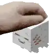 a person 's hand is holding a small white cube .