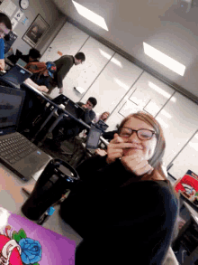 a girl with glasses is sitting at a desk with a dell laptop