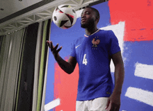 a man in a blue jersey with the number 4 on it holds a soccer ball