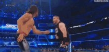 a wrestler is standing in a wrestling ring while a referee watches .