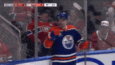 a hockey player wearing an edmonton oilers jersey holds a hockey stick
