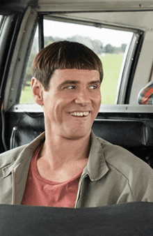 a man with a very short haircut is sitting in the back seat of a car