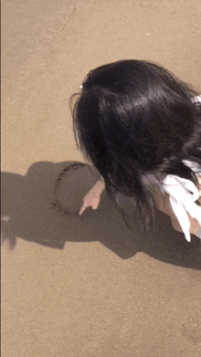 a girl is drawing a circle in the sand