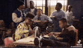 a group of people are sitting around a table with a boombox in the background
