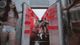 a group of women are standing in front of an open refrigerator filled with coca cola