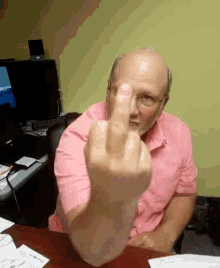 an older man in a pink shirt is giving the middle finger