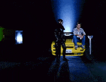 a man sitting on the hood of a yellow car with a mask on says i long for the dumpster