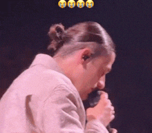 a man in a ponytail is singing into a microphone while crying .