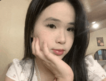 a woman with a hand on her face is looking at the camera