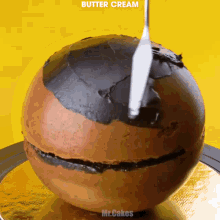 a chocolate ball is being decorated with butter cream by mr.cakes