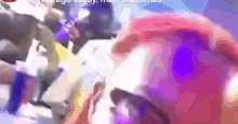 a close up of a person 's face with a purple background and a bunch of people .