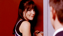 a woman is leaning against a red wall looking at a man .