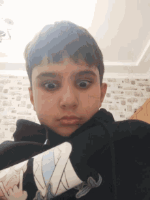 a young boy wearing a black shirt with a cartoon character on it looks at the camera