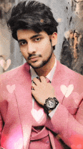 a man wearing a pink suit and tie has a watch on his wrist