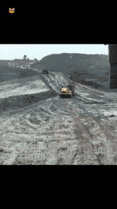 a yellow truck is driving down a dirt road with a smiley face on the bottom right