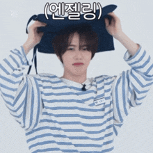a young man wearing a striped shirt is holding a blue bag on his head